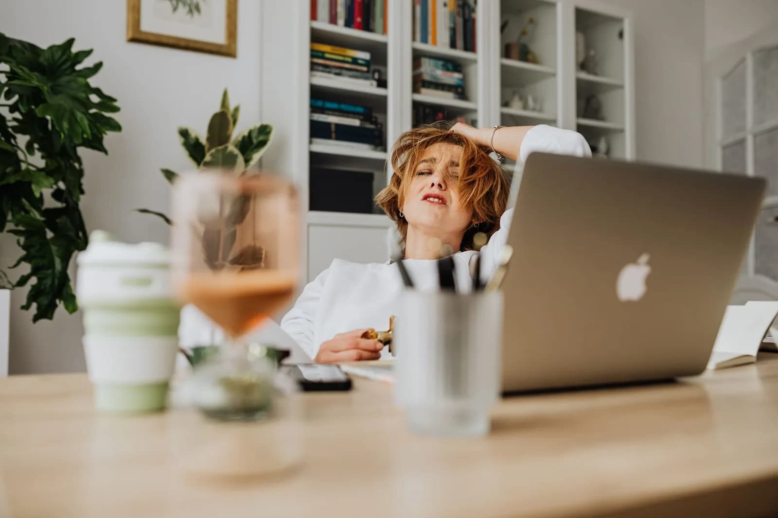 Mulher exausta em frente ao computador, com a mão na cabeça
