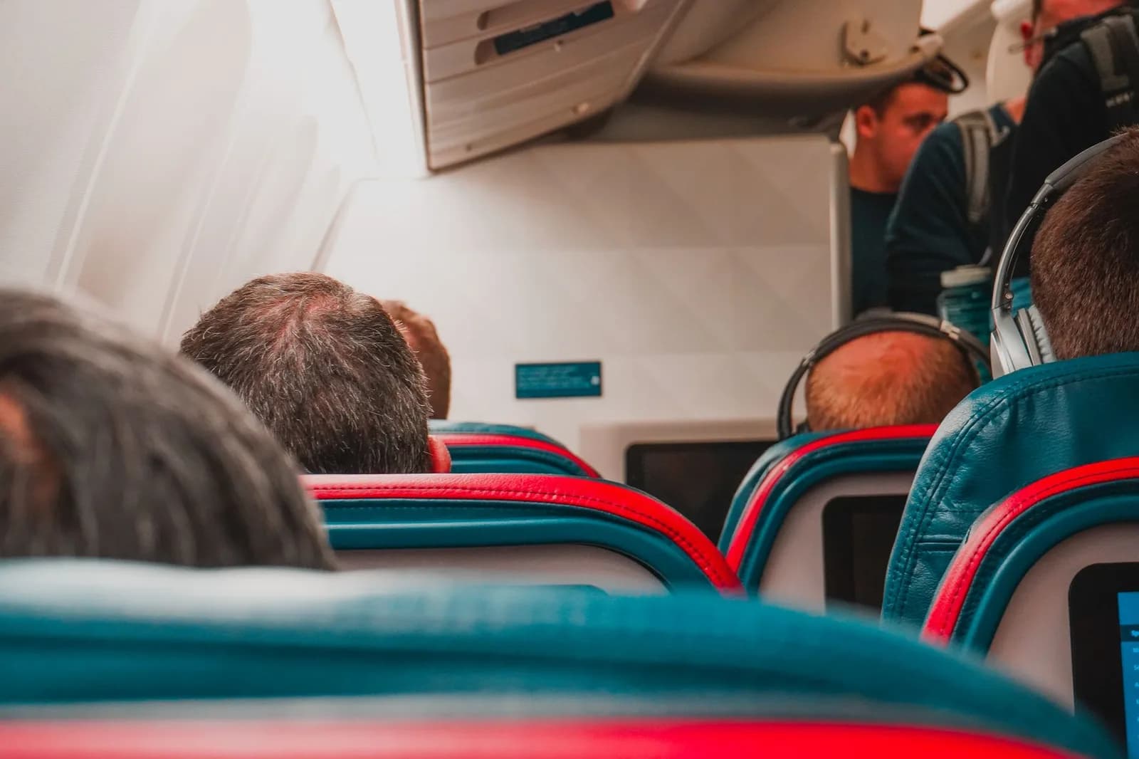Interior de cabine de avião com passageiros sentados aguardando
