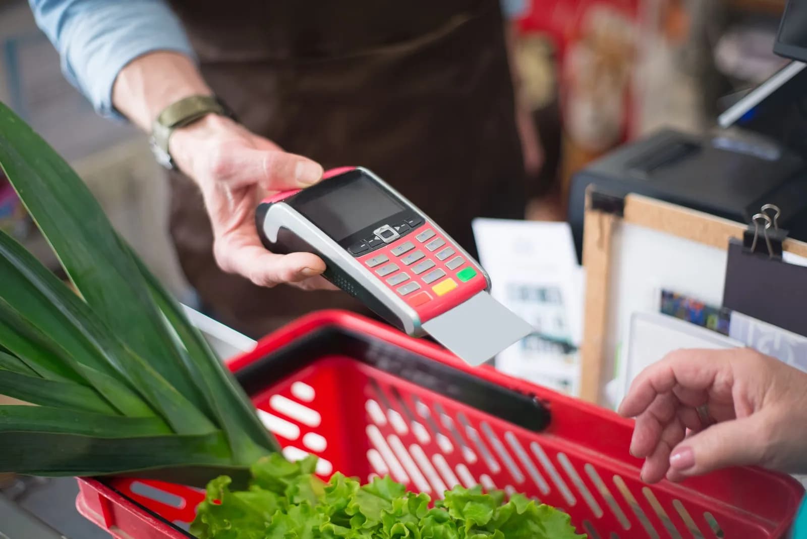 Atendente passa cartão na maquininha no caixa de um mercado