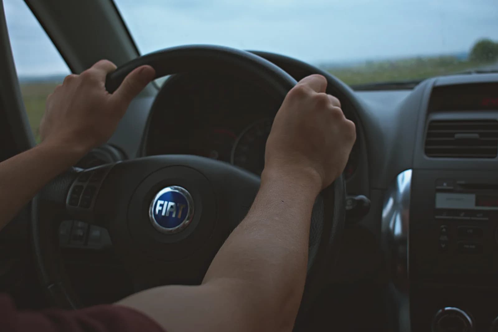 Motorista segurando o volante ao conduzir veículo em rua da cidade