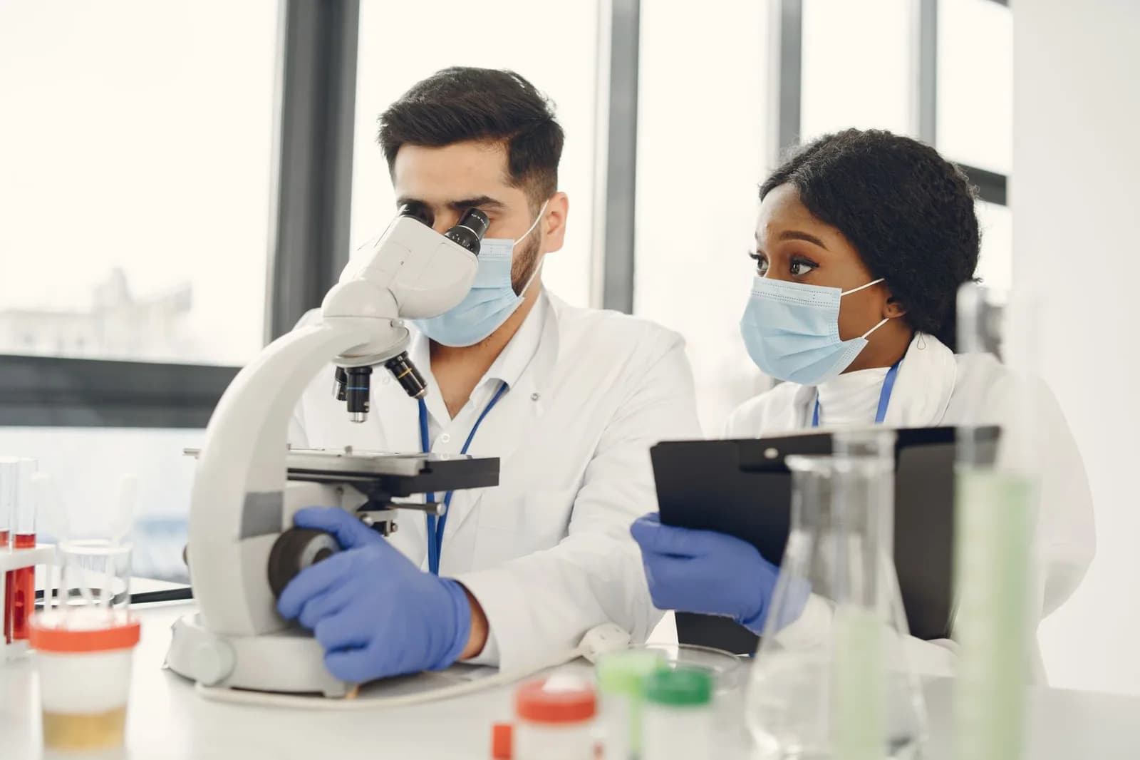 Pesquisadores em laboratório com jaleco branco analisando amostras oncológicas