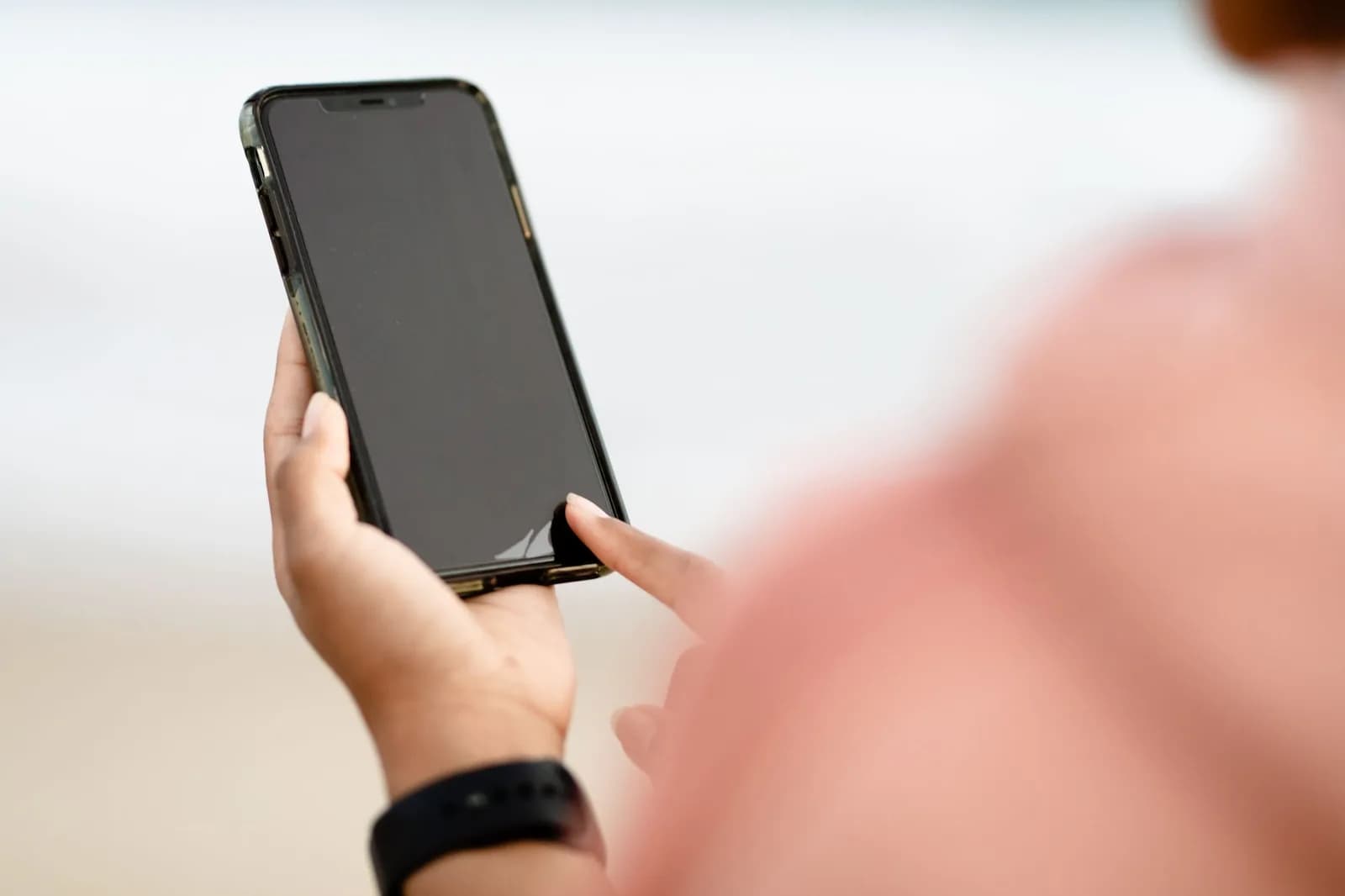 Mão segura um smartphone, dedo tocando a tela