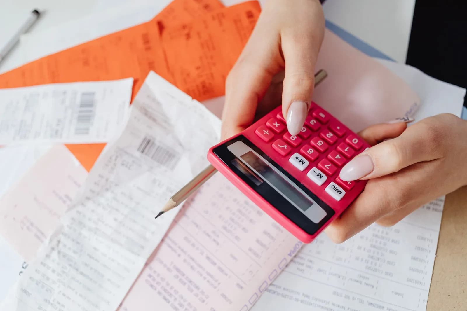 Mãos calculam recibos com uma calculadora sobre a mesa