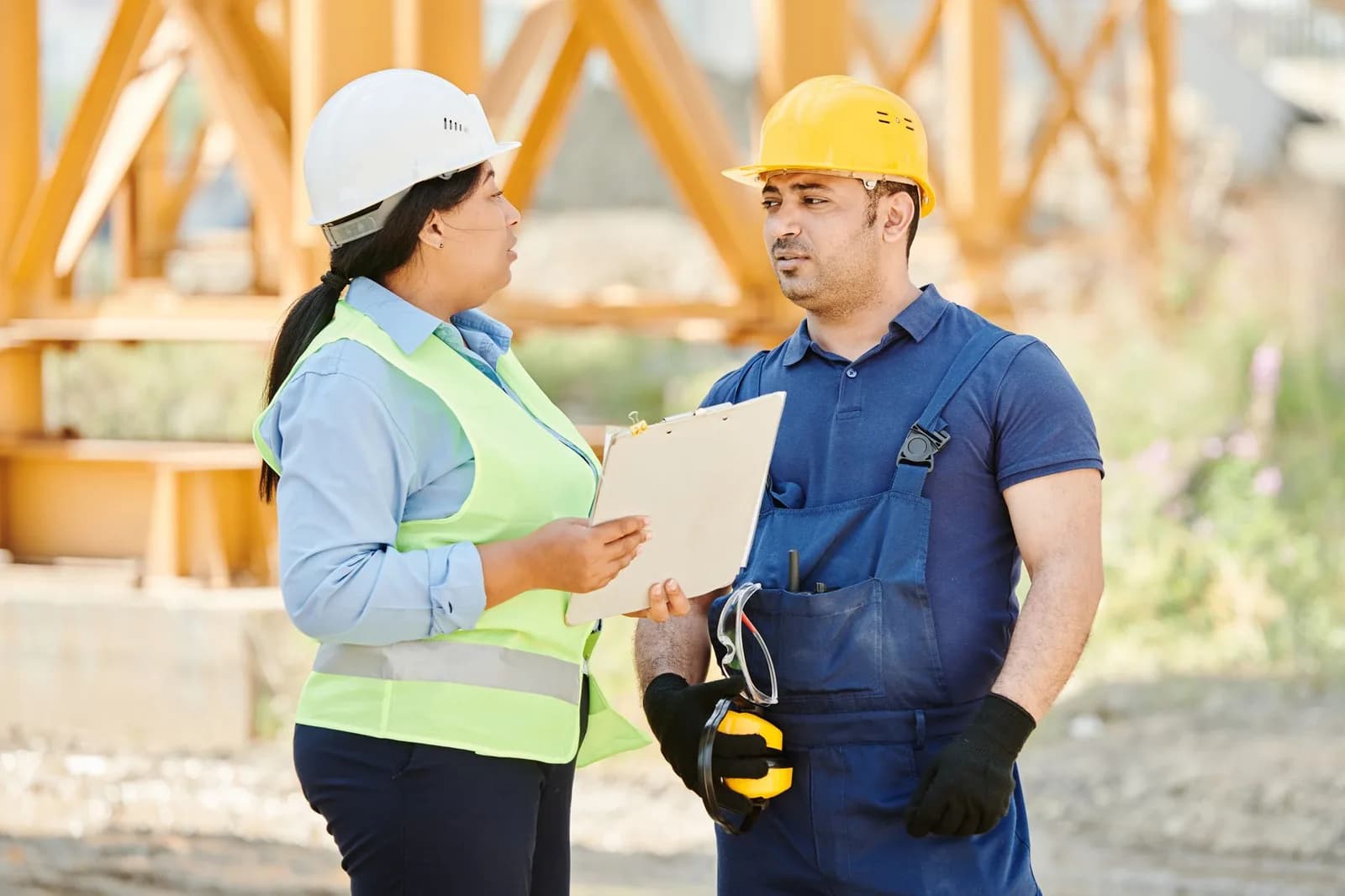 Fiscal de segurança do trabalho conversa com trabalhador de capacete em obra
