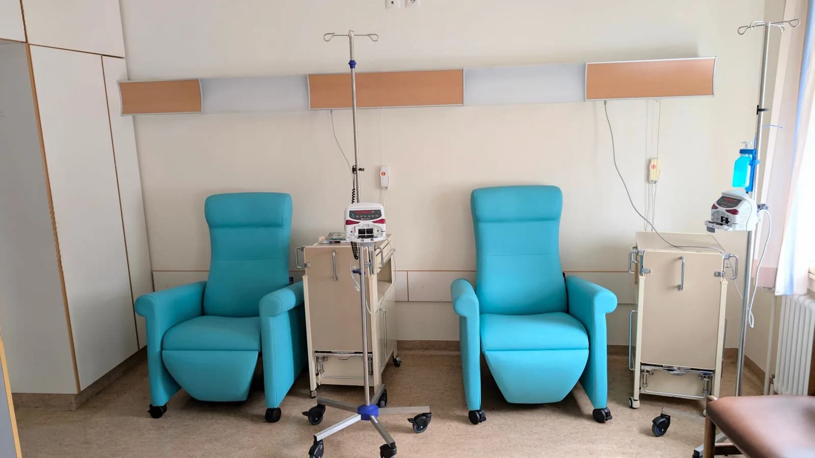 Sala de tratamento hospitalar vazia, com poltronas reclináveis para aplicação de soro