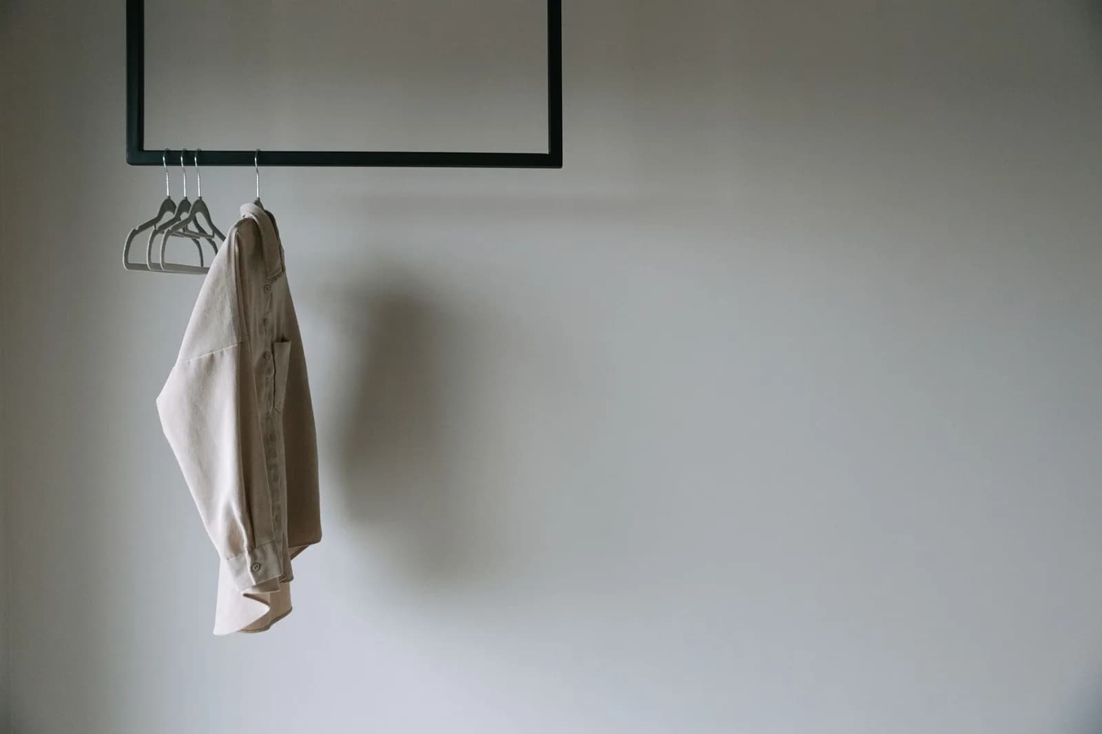 Camisa pendurada sozinha em um cabide, contra parede lisa