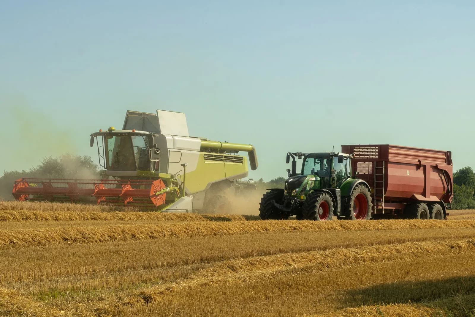 Colheitadeira e trator com carreta em lavoura