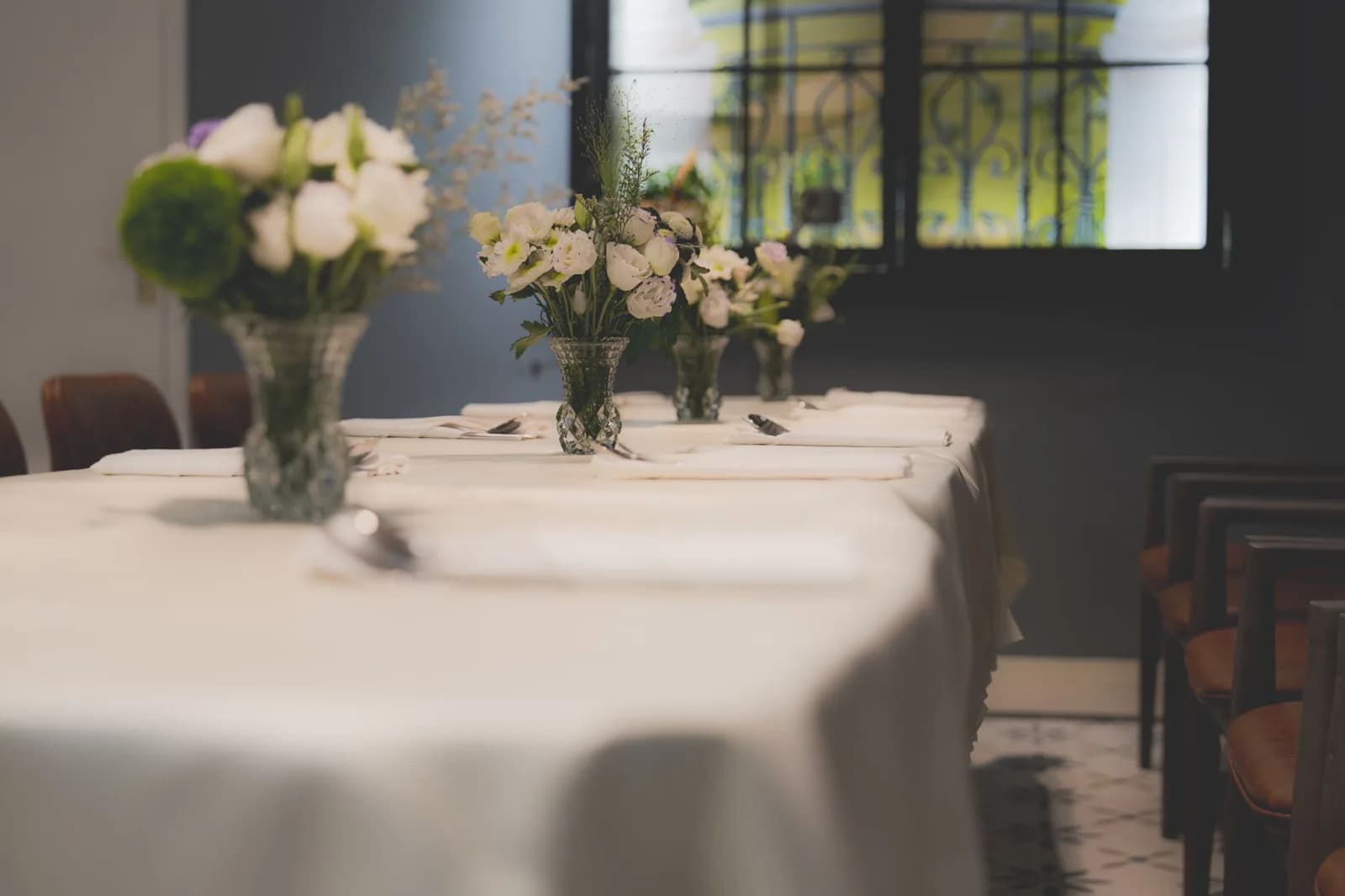 Mesa de restaurante com toalha branca e arranjo de flores