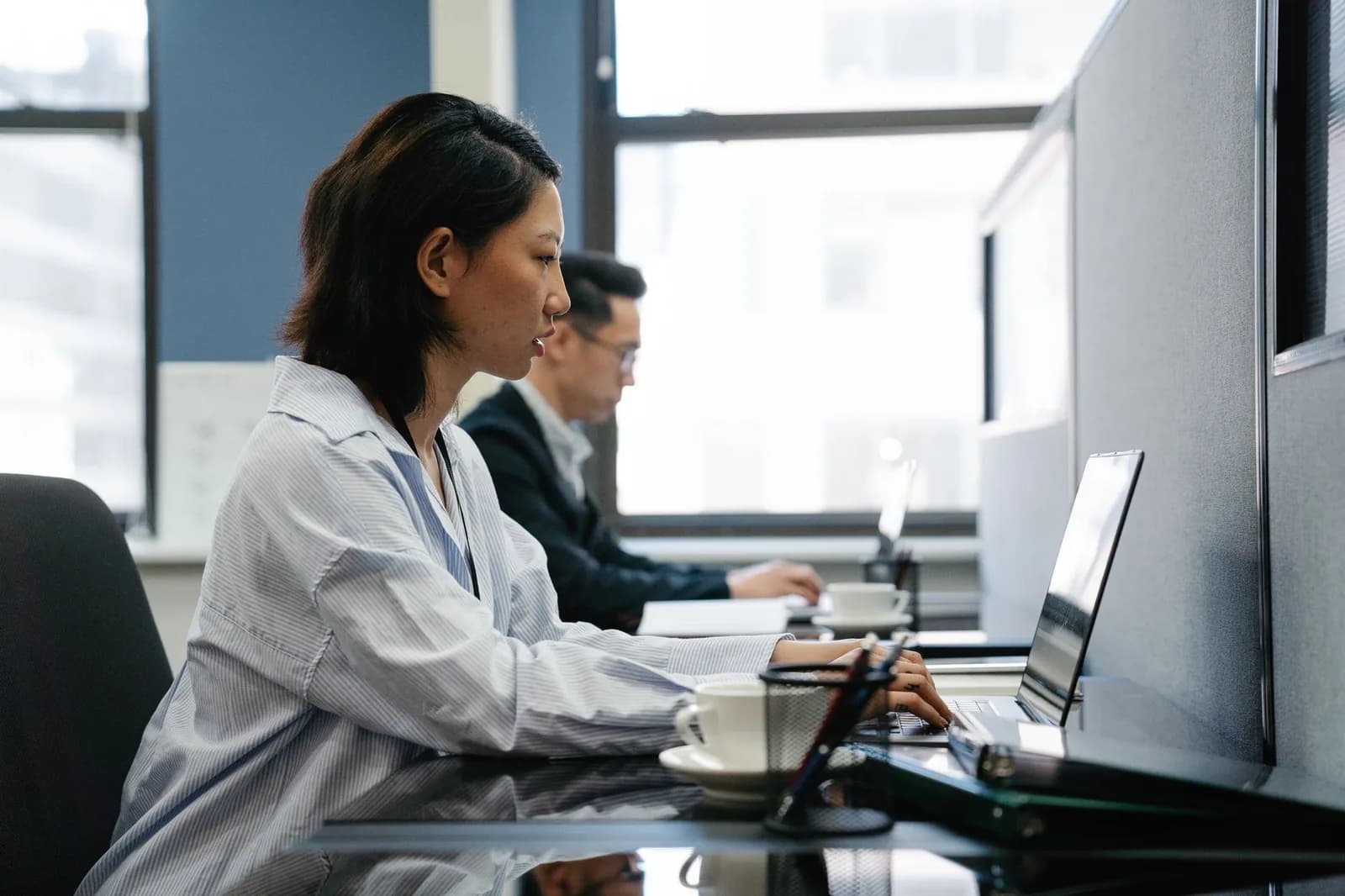 Trabalhadores em mesas de escritório usando computadores.