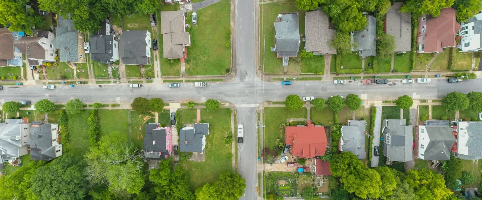 Vista aérea de rua residencial com casas e árvores.
