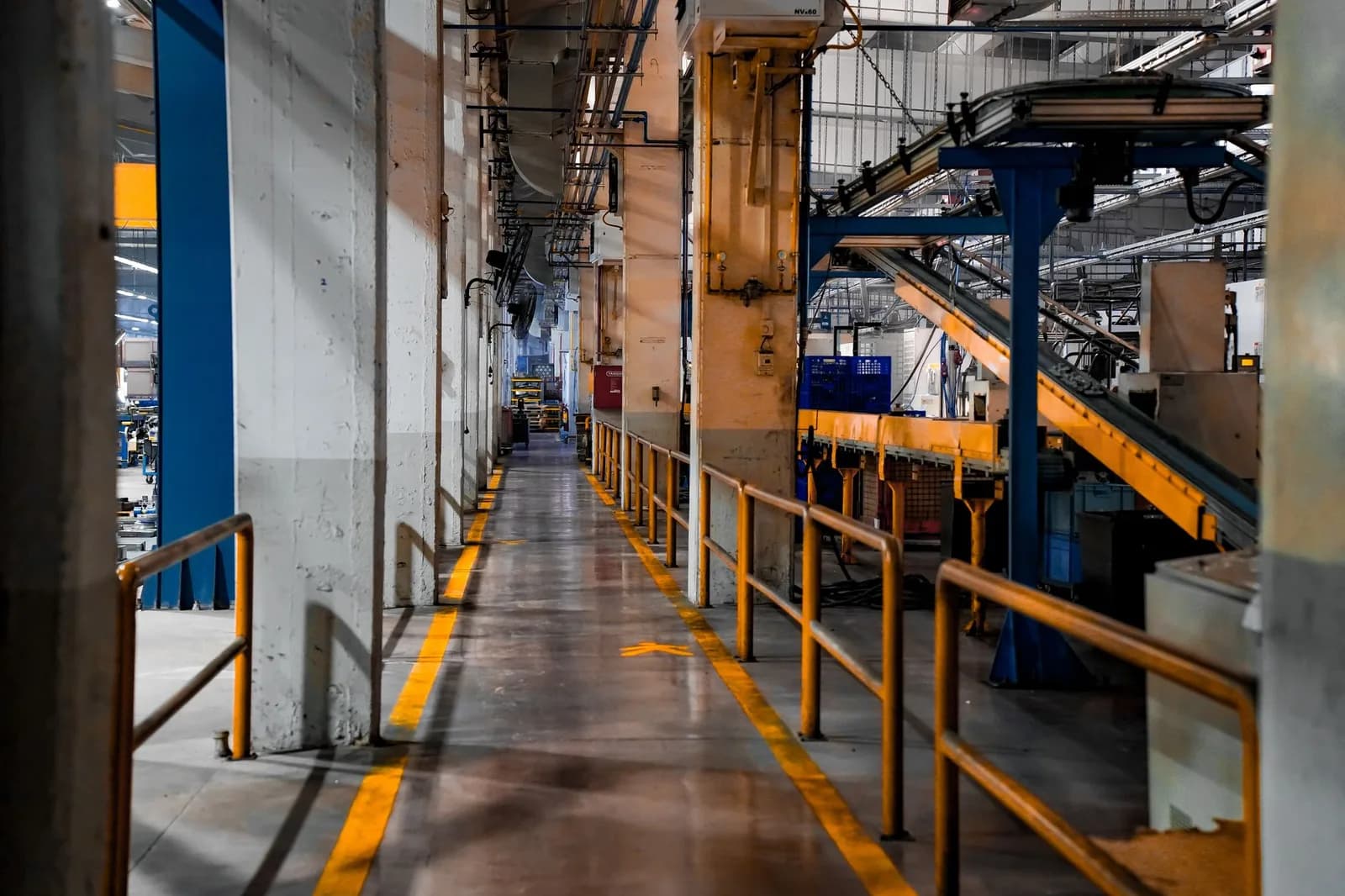 Corredor de fábrica com esteiras e corrimões amarelos