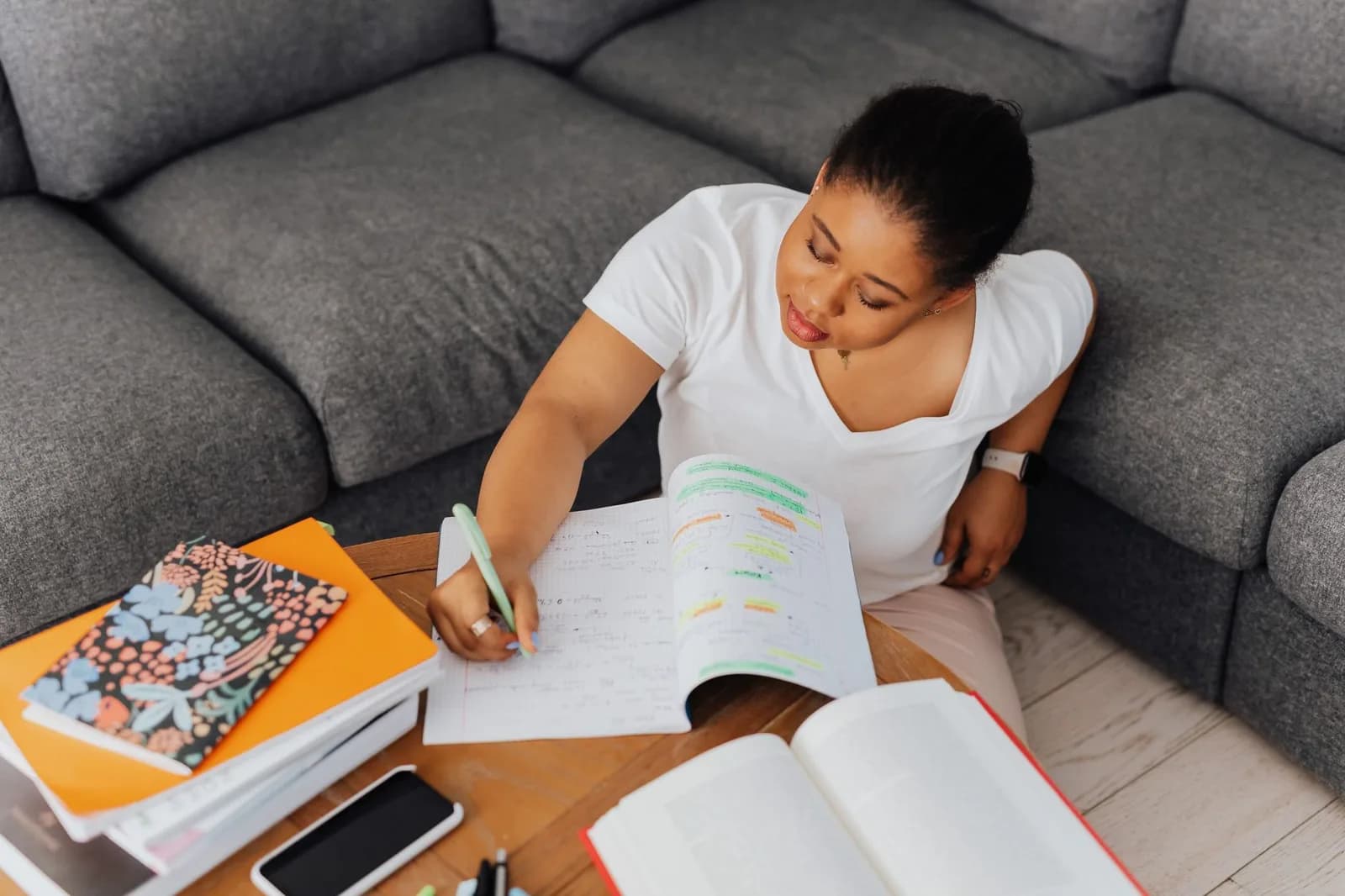 Mulher estudando com caderno e livros na sala de casa