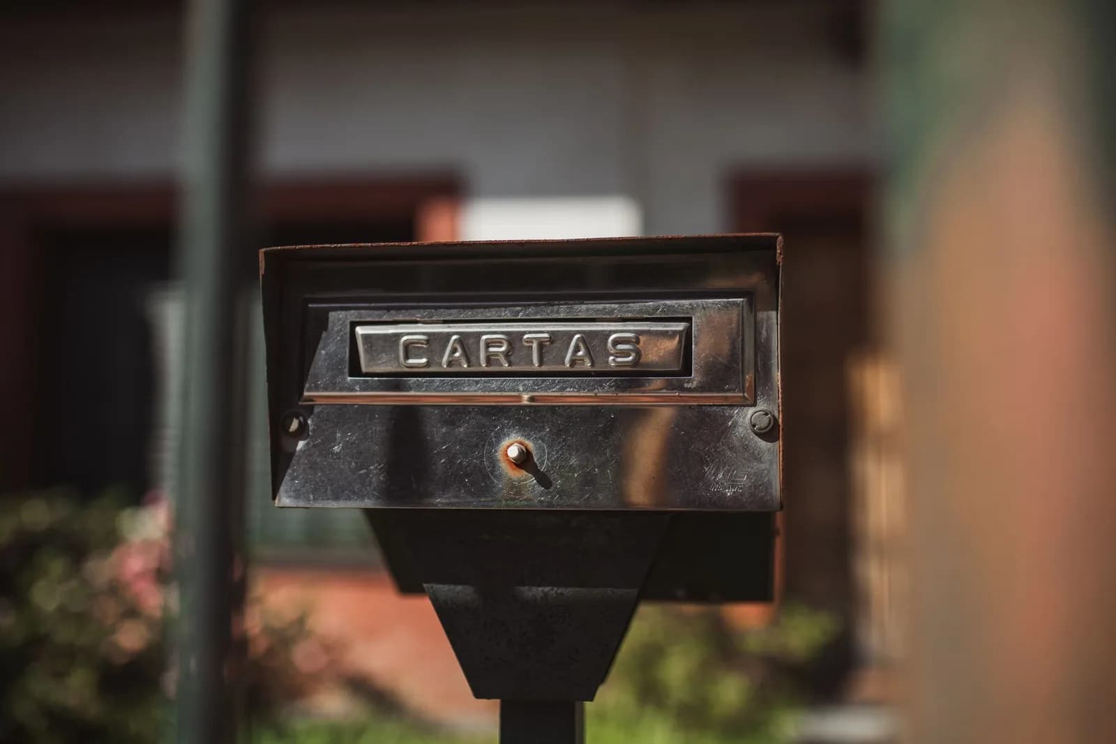 Caixa de correio de rua com a palavra CARTAS, em dia ensolarado