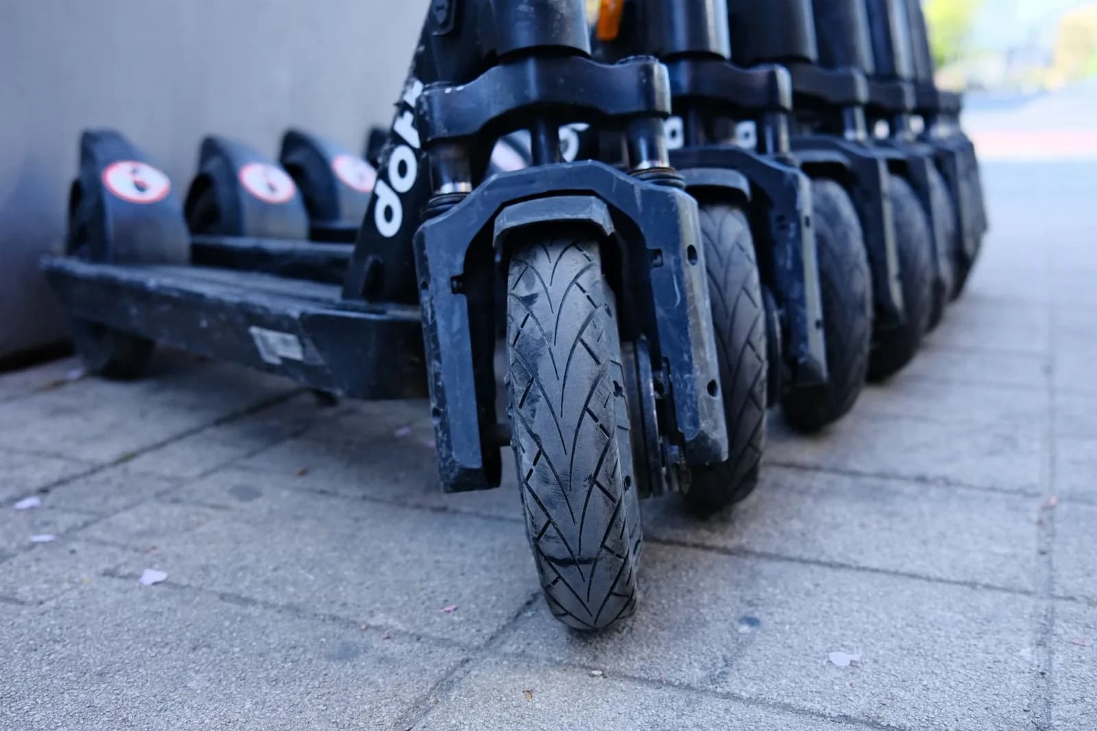 Fileira de patinetes elétricos estacionados lado a lado, em close nas rodas