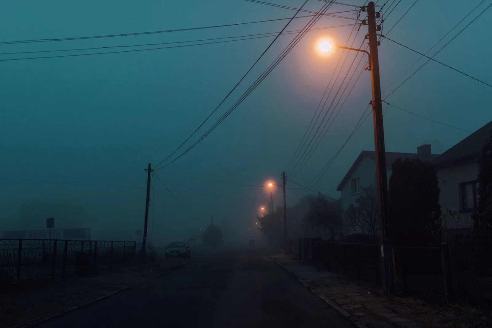 Rua escura com fios de energia eletrica e poste durante temporal e falta de luz