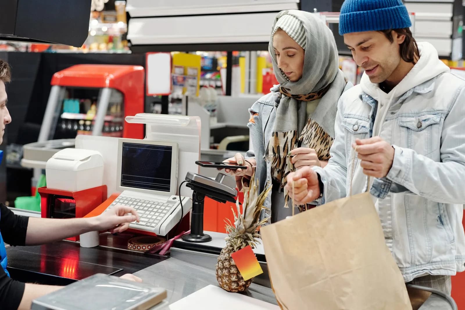 Operador de caixa atendendo clientes no caixa de supermercado durante jornada de trabalho