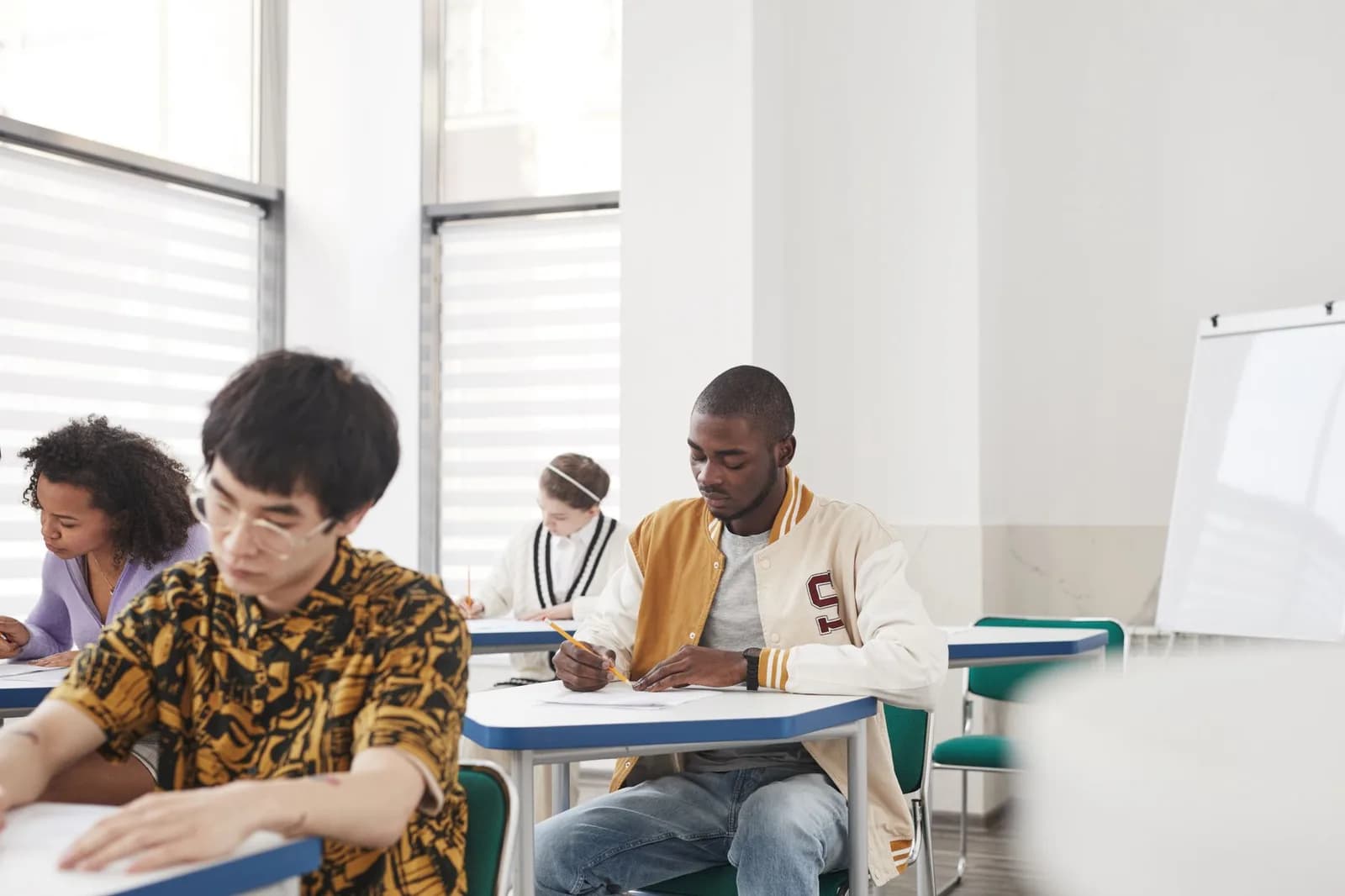Estudantes concentrados fazendo prova em sala de aula