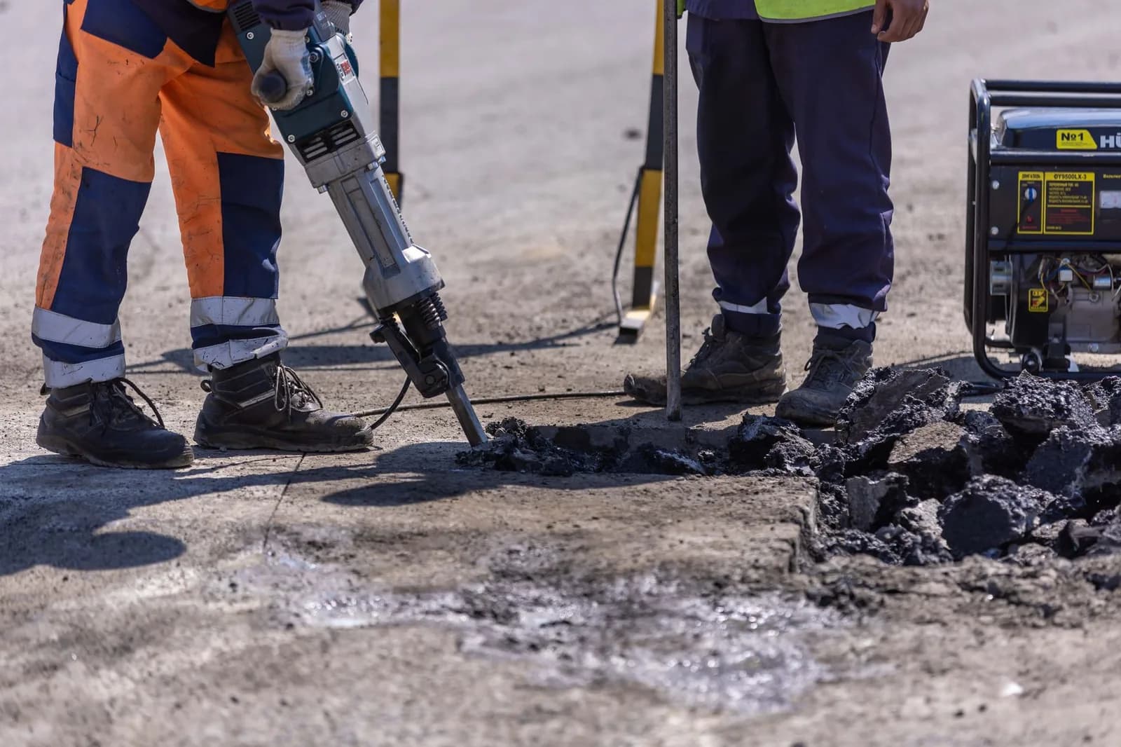 Operários com martelete rompendo o asfalto para reparar a rua.
