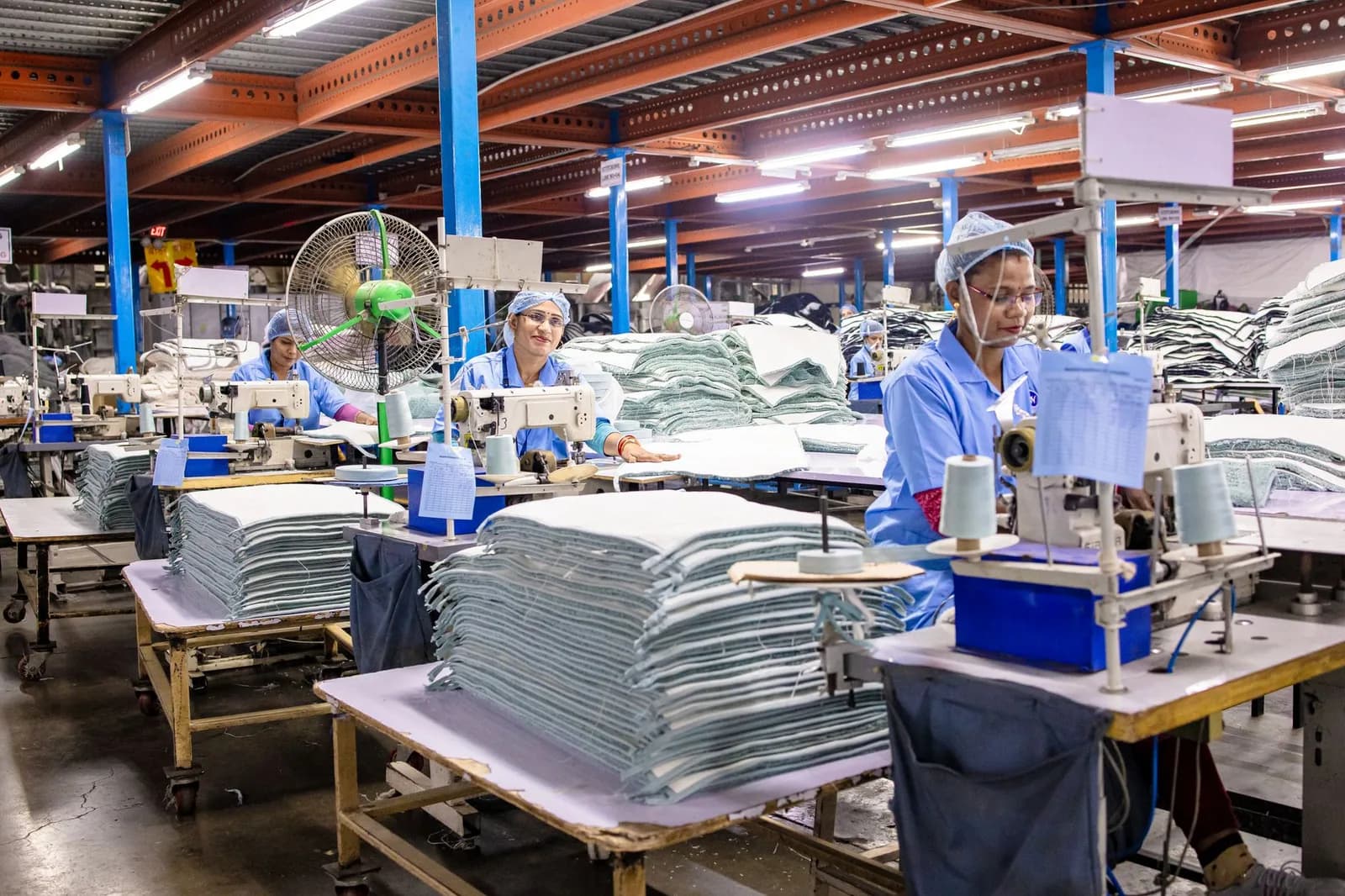 Operárias trabalham em linha de costura em fábrica têxtil