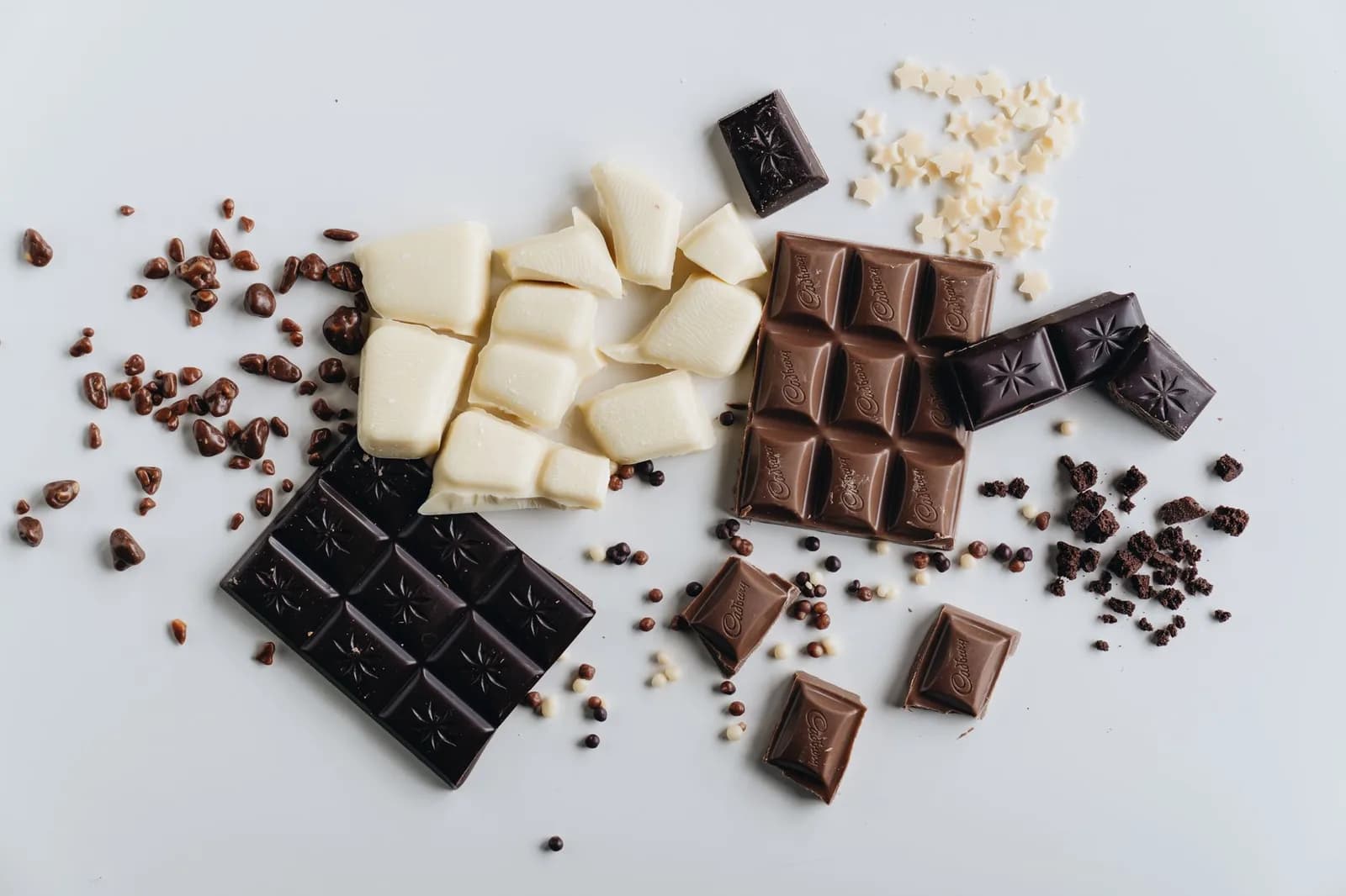 Barras de chocolate ao leite, amargo e branco sobre uma superfície clara