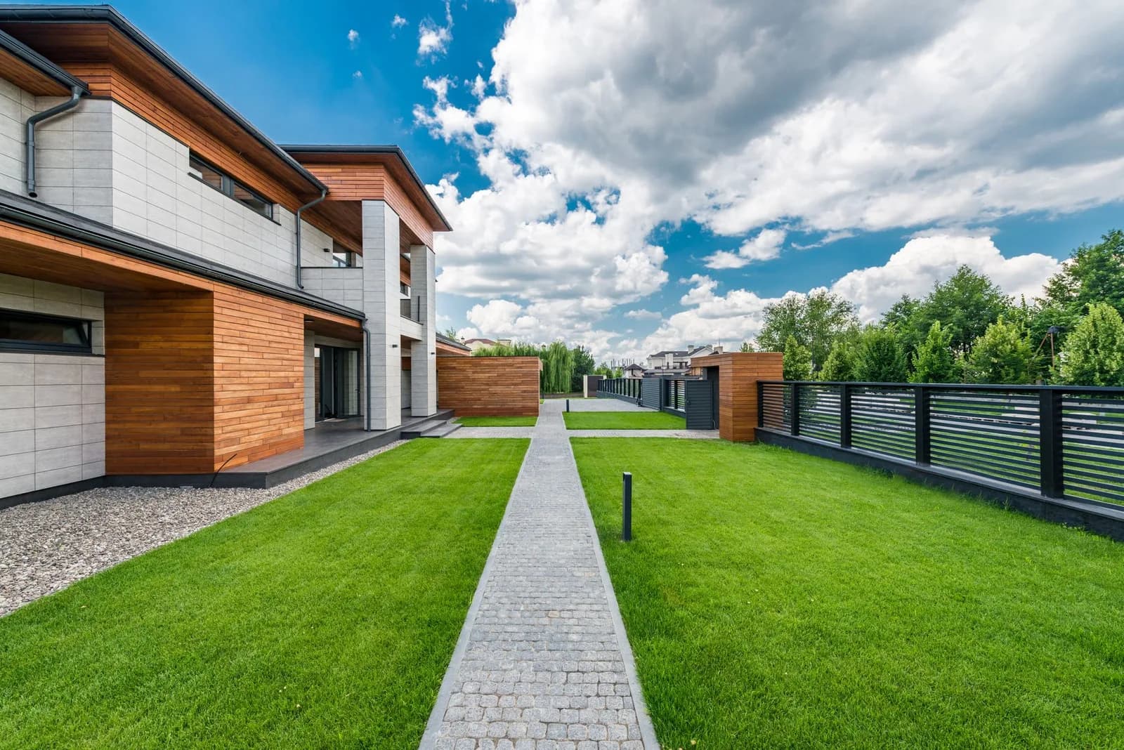 Casa moderna com jardim gramado e caminho de pedra sob céu azul