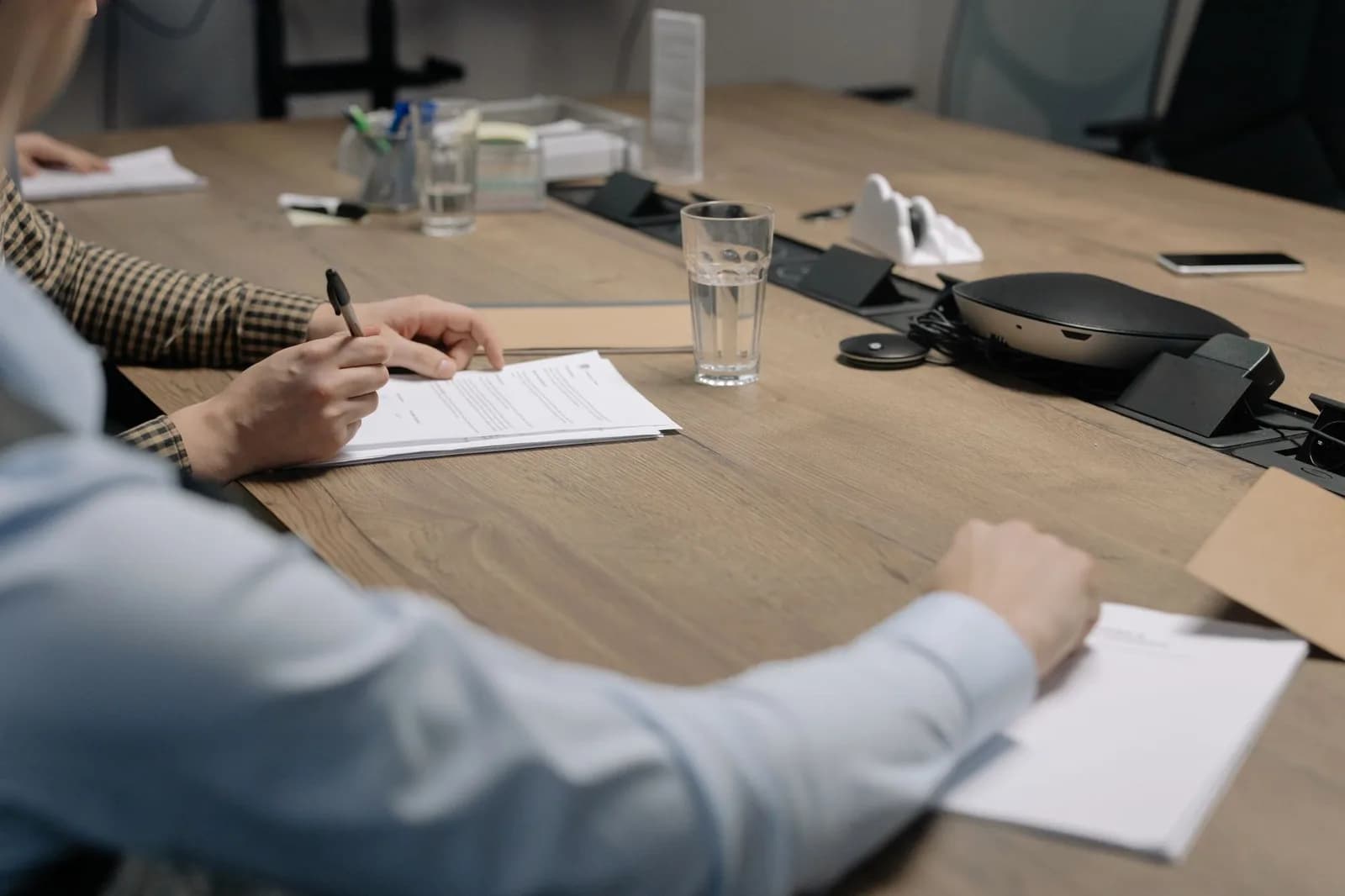 Pessoas escrevem em papéis sobre uma mesa de escritório